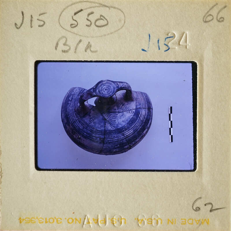 Ancient pottery displayed on a white surface with visible cracks and markings.