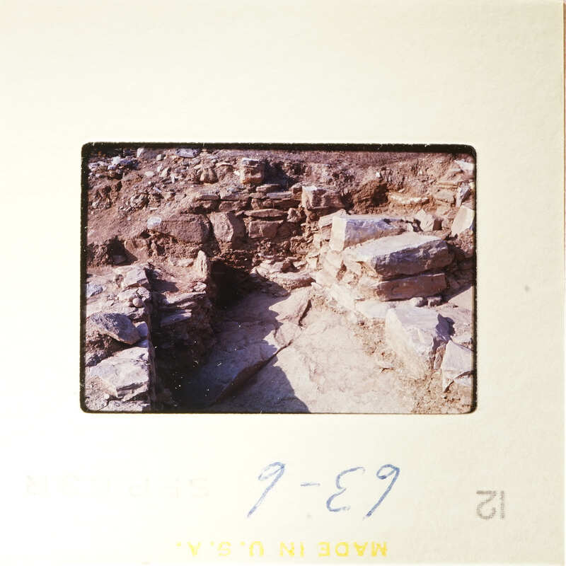 Old photograph showing ruins with stone walls and dirt ground.