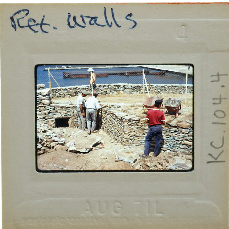 A vintage photograph of workers constructing a stone wall near water.