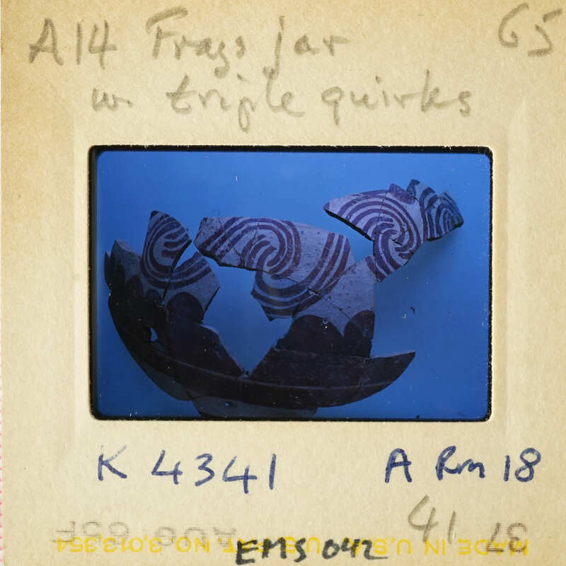 A photograph of an ancient pottery fragment with swirling patterns.