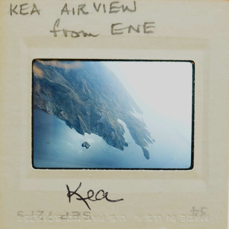 Aerial photograph of a coastline with mountains and water, labeled "KEA AIR VIEW" and the name "ENE".
