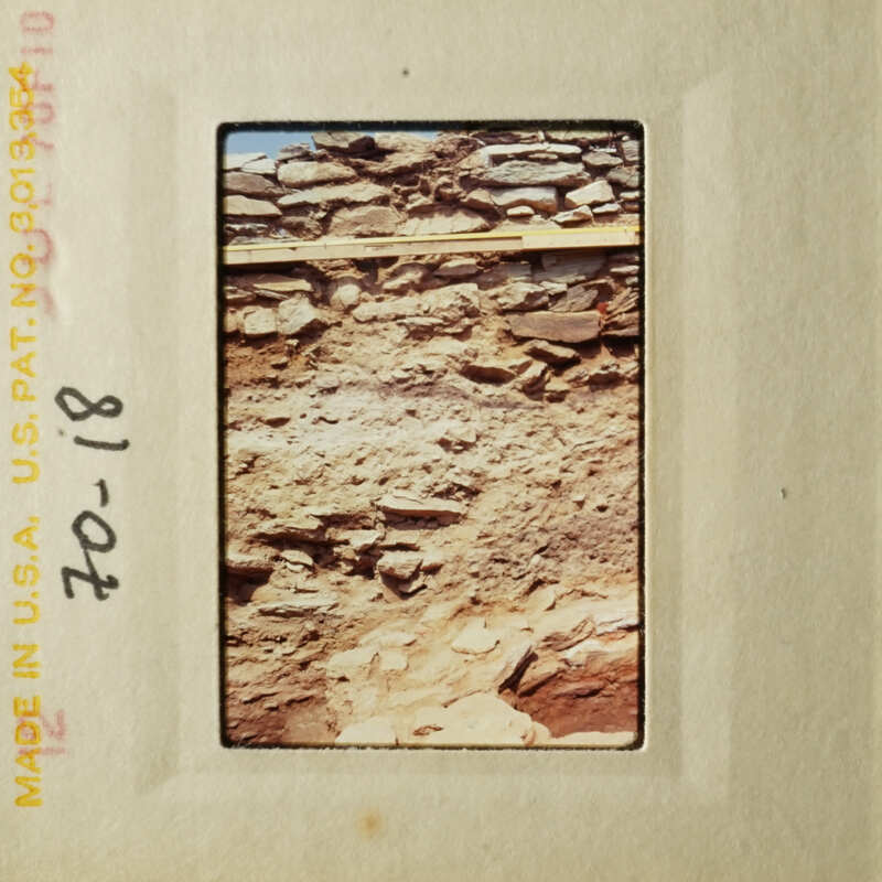 This is an image of a slide showing a barren, rocky landscape with some vegetation and a building.