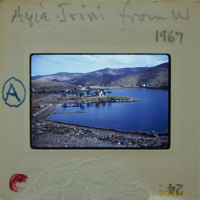 A vintage photo of a scenic landscape with a body of water and mountains, taken from an elevated perspective.