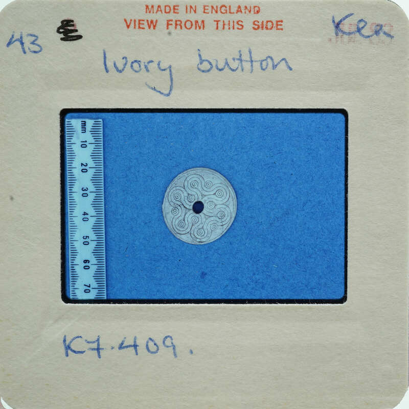 A close-up image of a button on a measuring tape, with labels and measurements indicating its size.