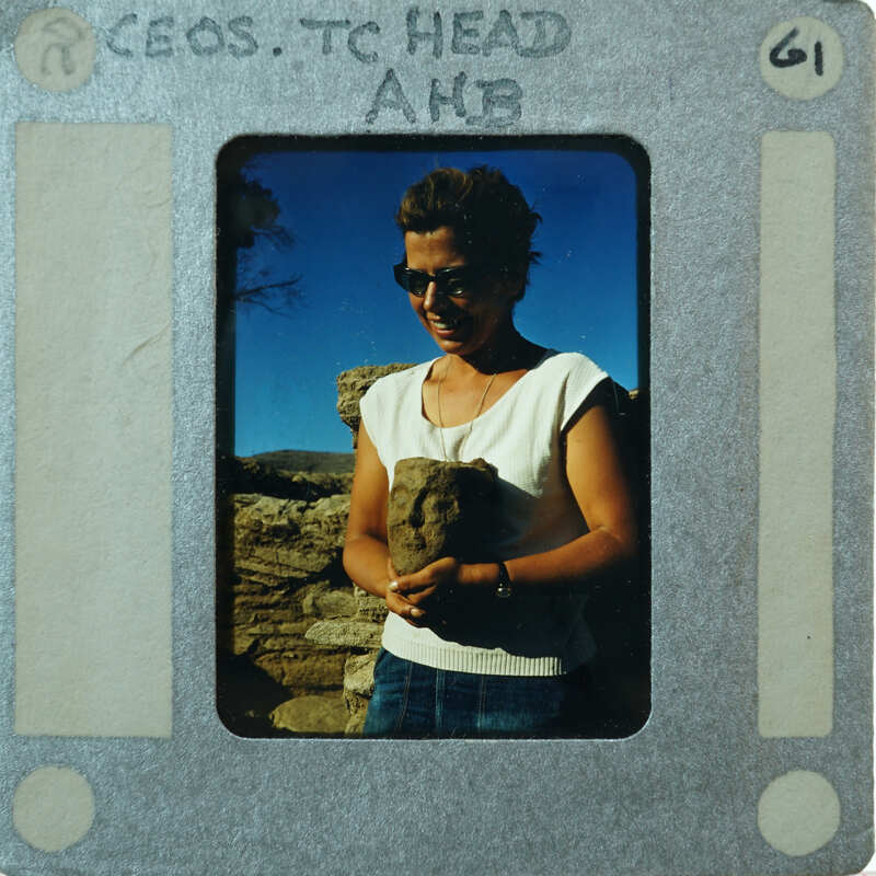 Woman holding a terracotta head, smiling at the camera.