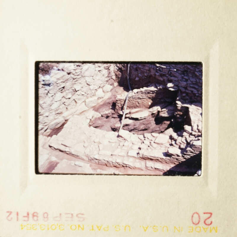 This photo shows an archaeological site with stone ruins and a person standing near them.