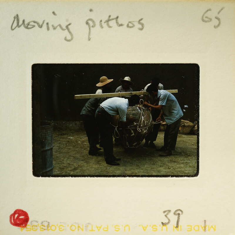 A group of men working on a large clay pottery piece.