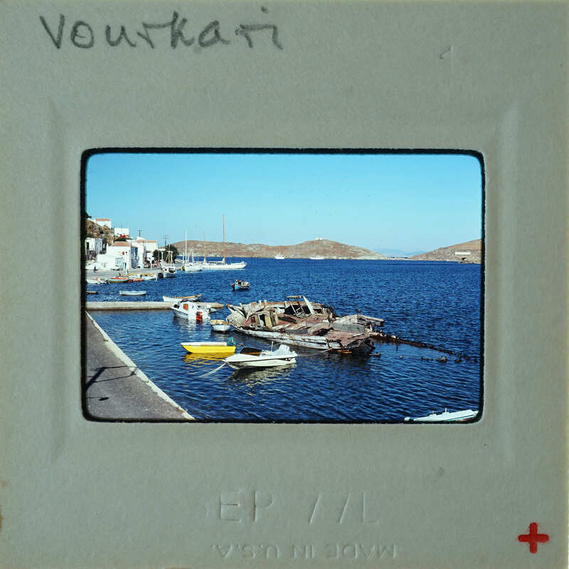 A photograph of a harbor with boats and calm waters, taken from a vintage Polaroid frame.