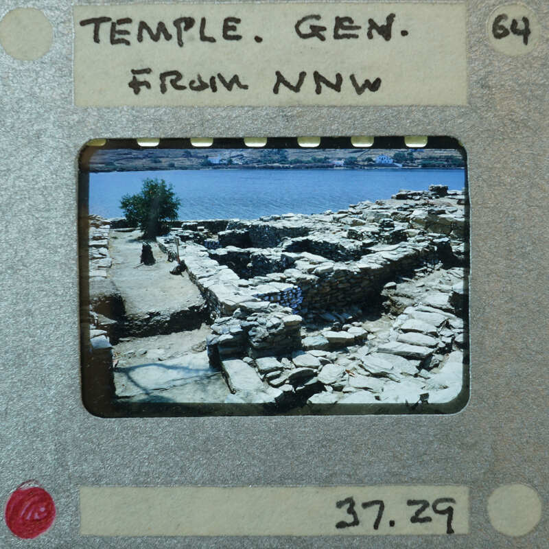 Temple wall ruins from a distance with a tree and water above.