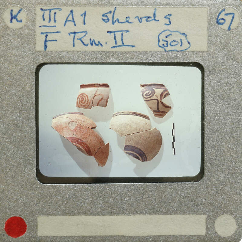 Five partially reassembled decorated pottery sherds on a display card.