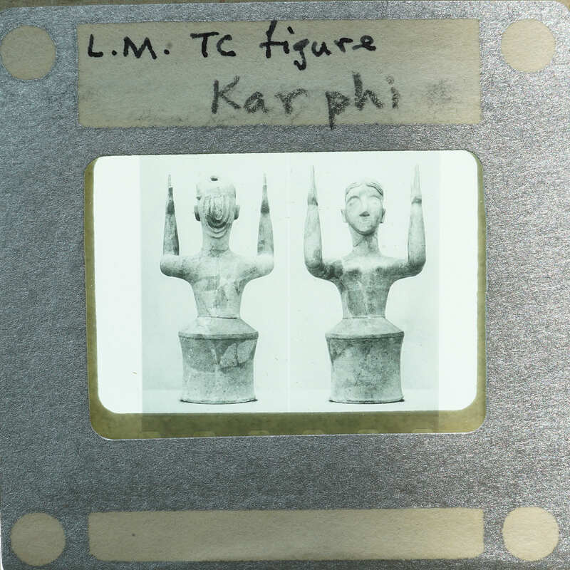 A black and white photograph of two ancient Greek vases with a label reading "LM TC Figure Karpoi".