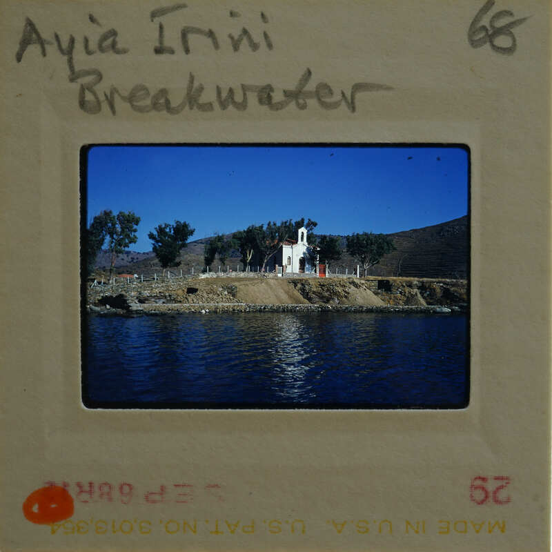 A vintage photograph of a church by the water with trees and mountains in the background, displayed on an old film strip.