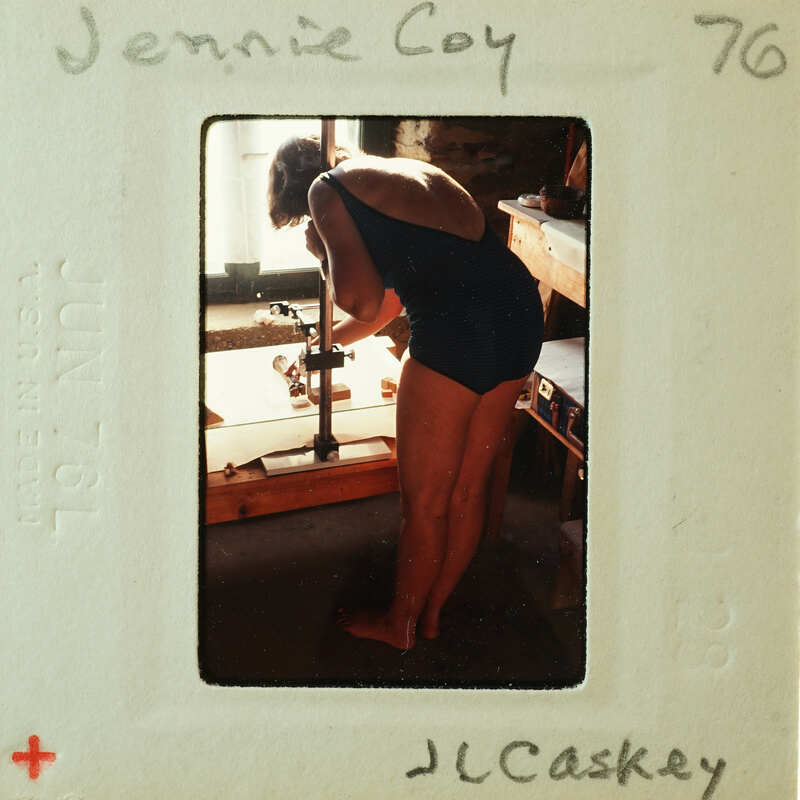 Woman wearing a swimsuit, bending over and working on something with her hands.