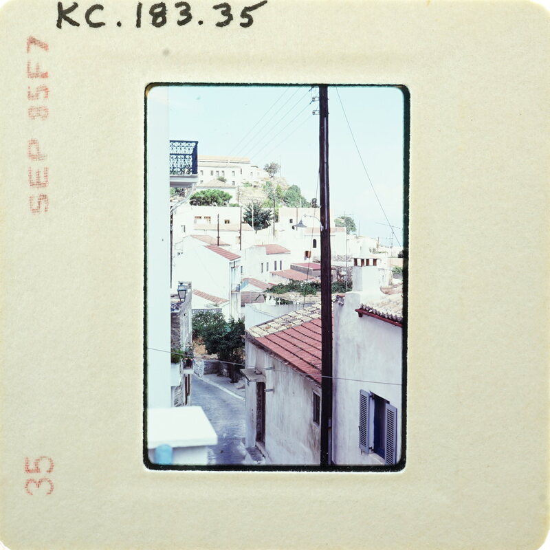 Photo of a village with stone houses and power lines, taken from an elevated perspective on film with a white border.