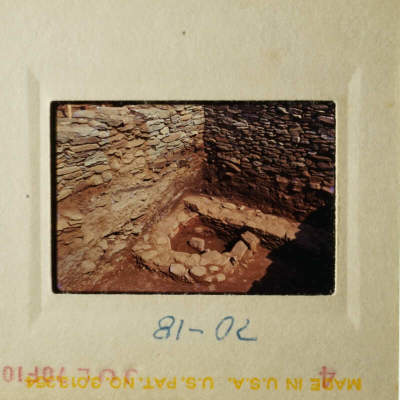 The photo shows an ancient stone structure, possibly a well or pit, surrounded by stones and rocks, with a small opening at the top.