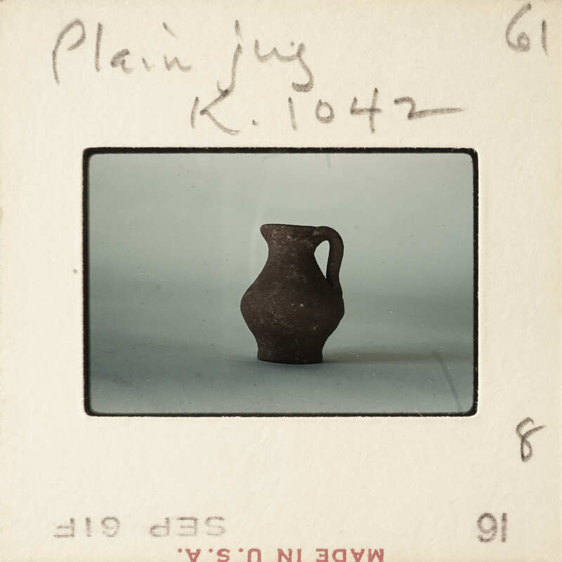 A photograph of a small, dark-colored vase on a plain background.