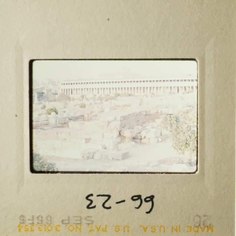 The photo shows an old cityscape with a prominent building and ruins, taken from a distance.