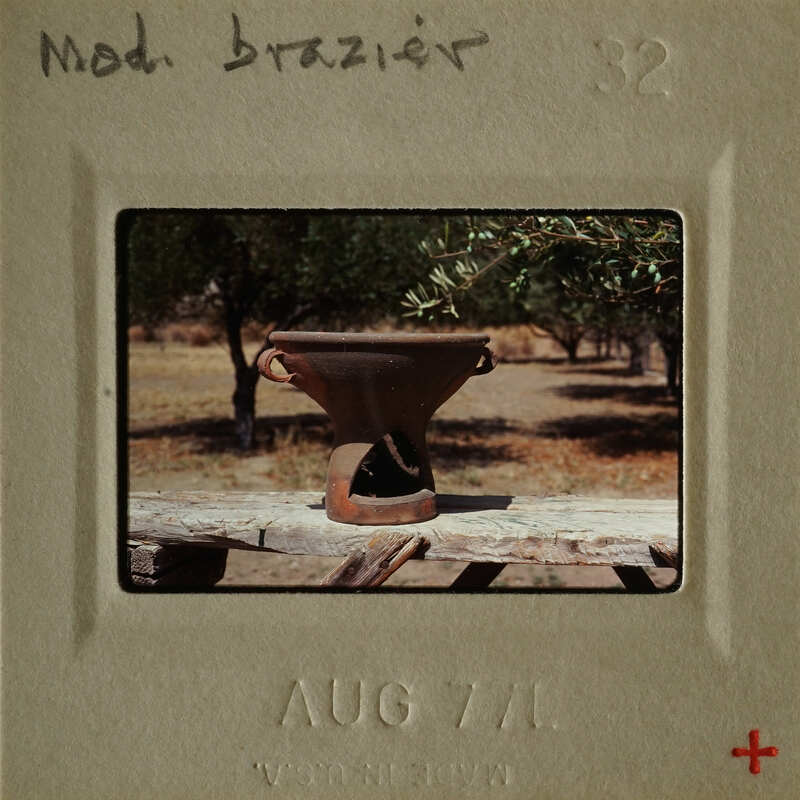 Ancient pottery on wooden table with trees in background.