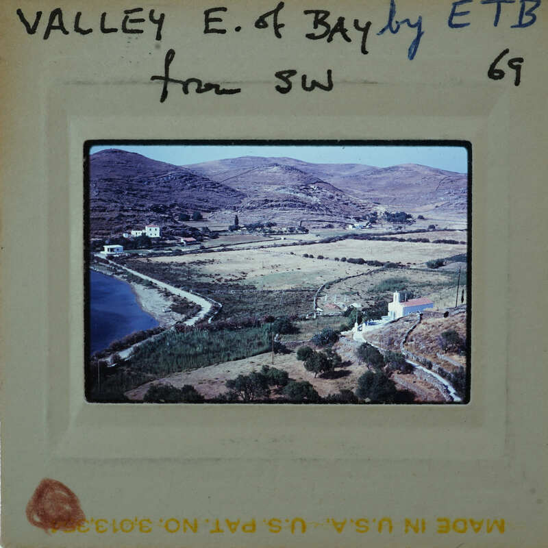 This is a vintage photograph of a valley with mountains and a body of water, enclosed within an old film negative frame.