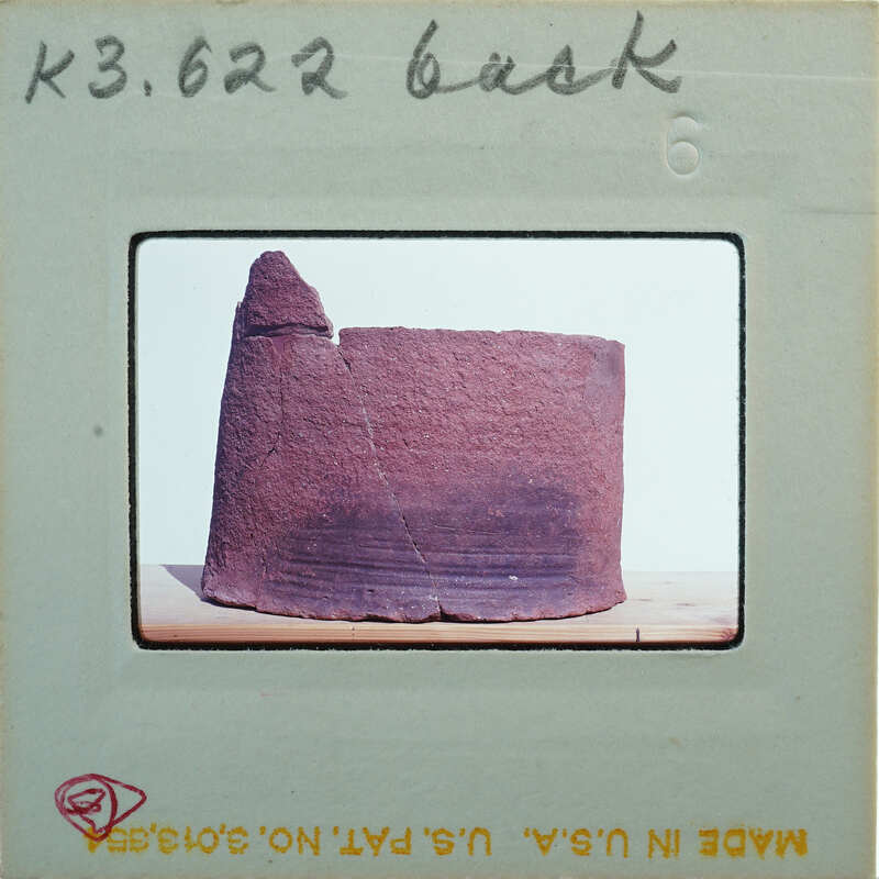 Broken base of terracotta figurine skirt from back.