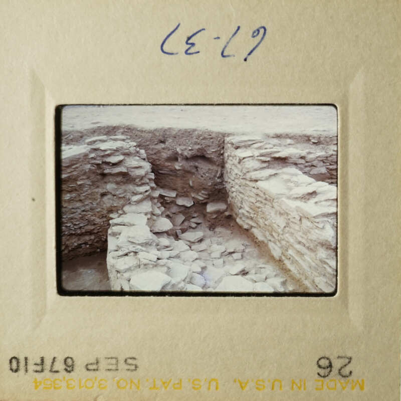 This is an old photograph depicting a stone wall and a barren landscape.