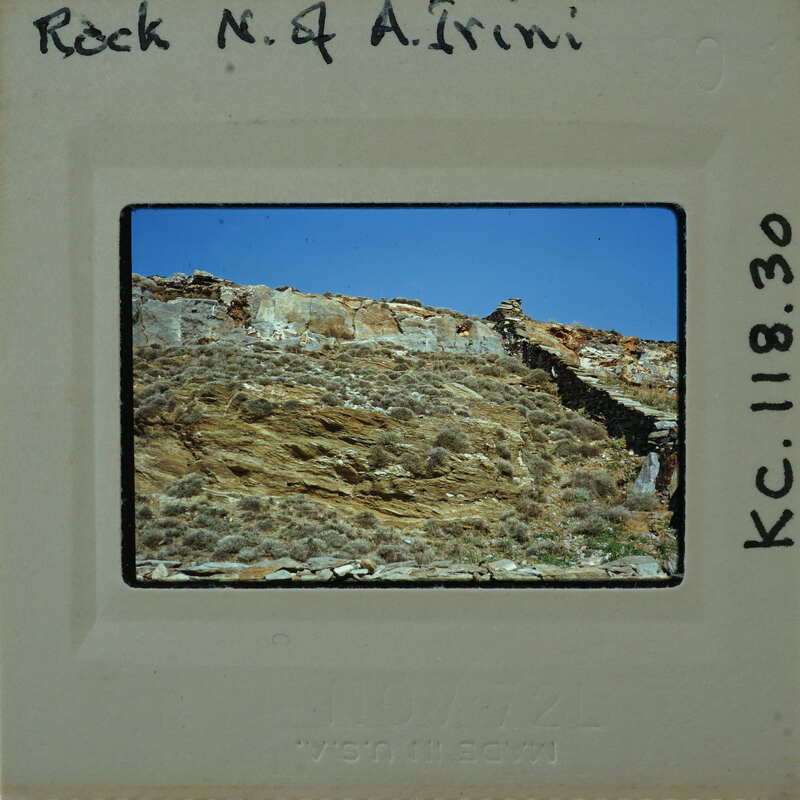 A vintage photograph of a rocky cliff with vegetation, featuring an old-fashioned camera negative format with handwritten details on the border.