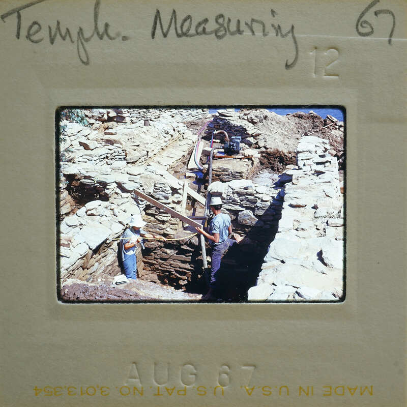 A black and white photo of archaeologists working on a dig site with ancient ruins.