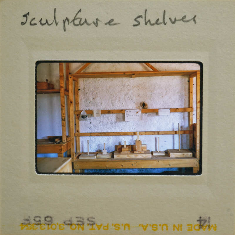 Wooden shelf with various items and a sign that says "SCULPTURE SHELF".