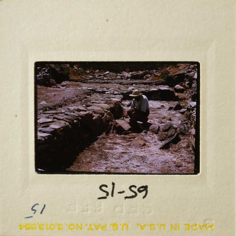 A man wearing a hat, working on stone ruins.