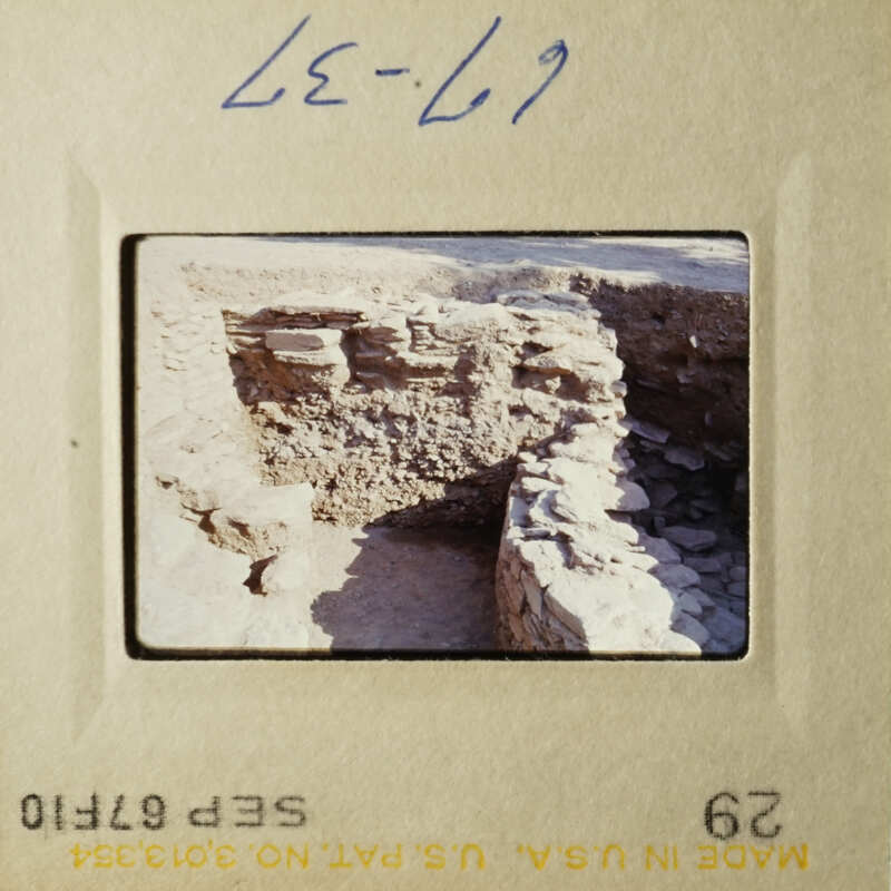The photograph shows an ancient stone structure, possibly ruins, with a view from above looking down into a pit or trench.