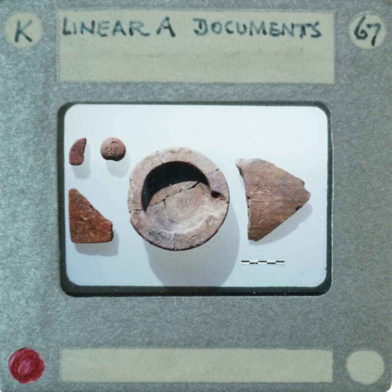 A small, broken clay pot with fragments on a display card.
