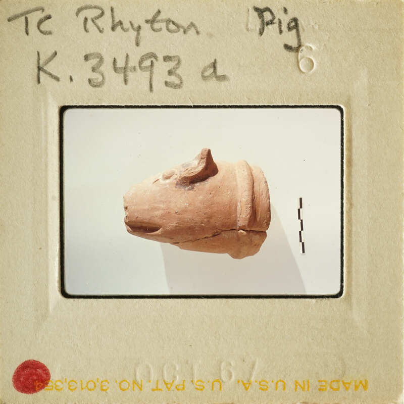 A clay sculpture of an animal, possibly a dog, displayed on a stand.