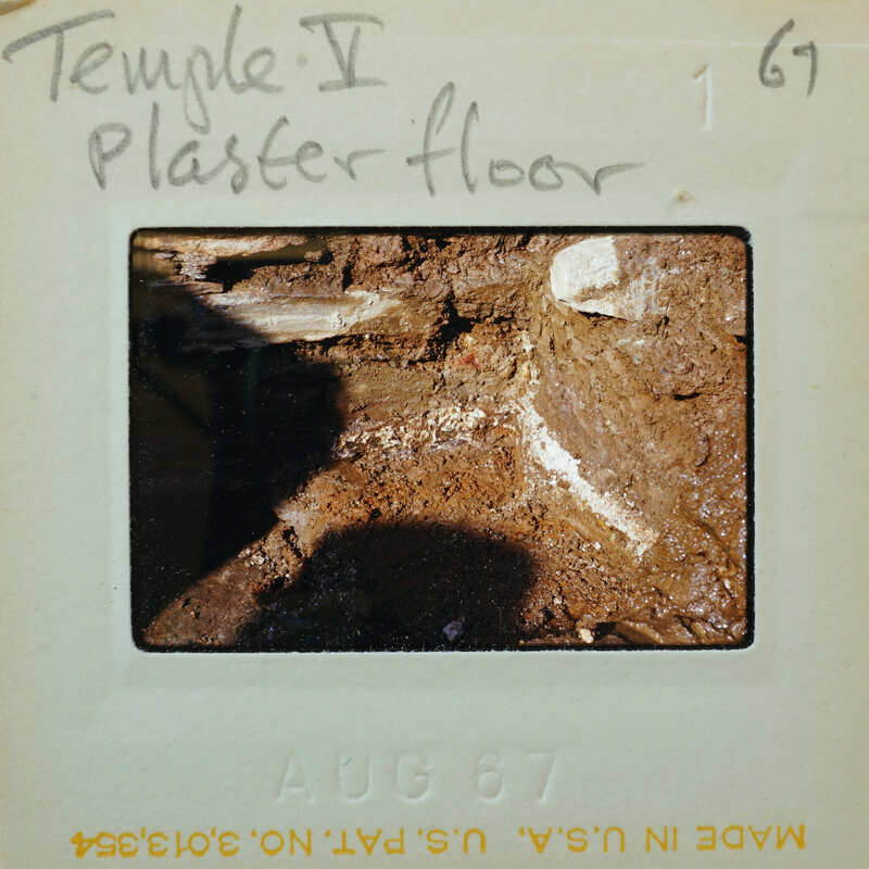 Muddy dirt floor with a line of white between the floor and the stone wall.