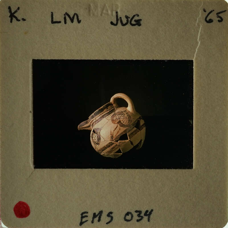 A small, intricately decorated vase with a handle on display.