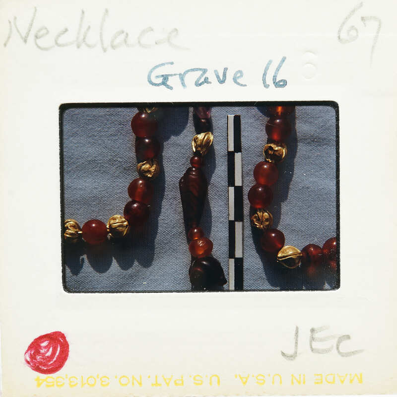 A necklace with red beads and gold accents displayed on a white surface.