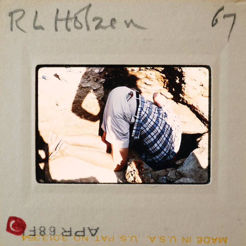 Person kneeling down, looking at something on the ground.