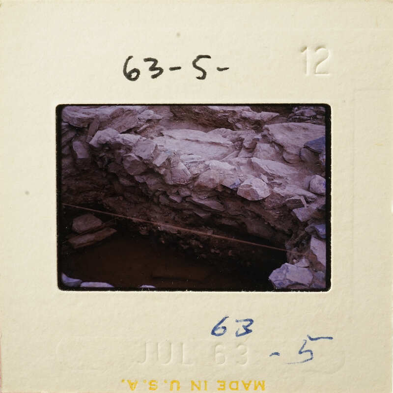 A photograph of an old stone structure with visible erosion and damage, possibly a bridge or wall.