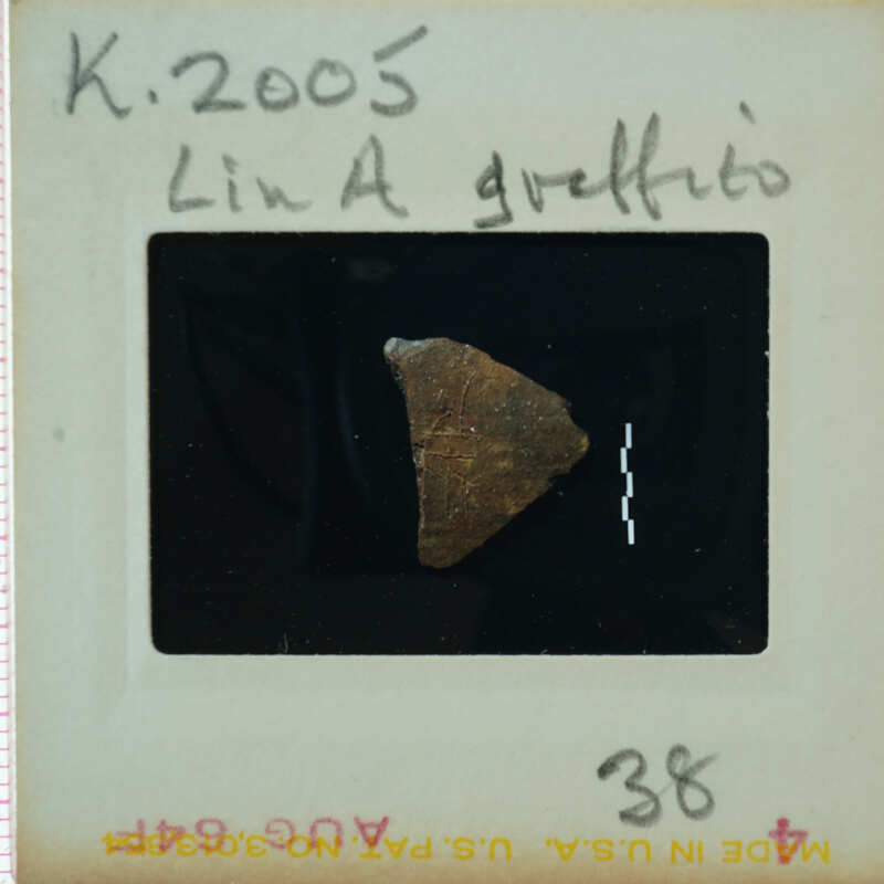 A small, irregularly shaped rock on a film negative with handwritten notes and numbers.