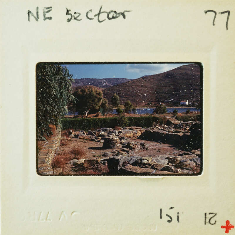 A vintage photograph of a landscape with mountains, trees, and ruins, with an overlaid negative strip showing the film roll number.