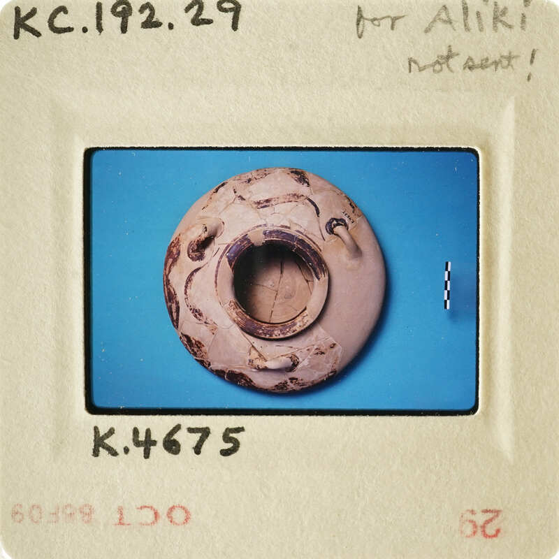 Small clay object with hole, photographed on blue background.