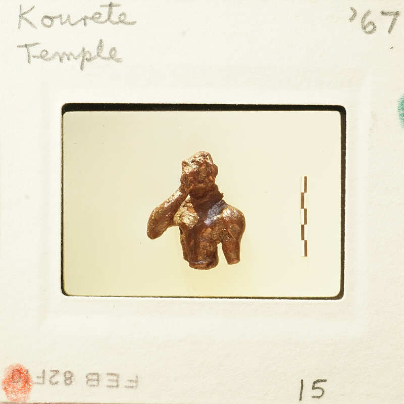 Small figurine of a person with hands raised, captured in a photograph on a white background.