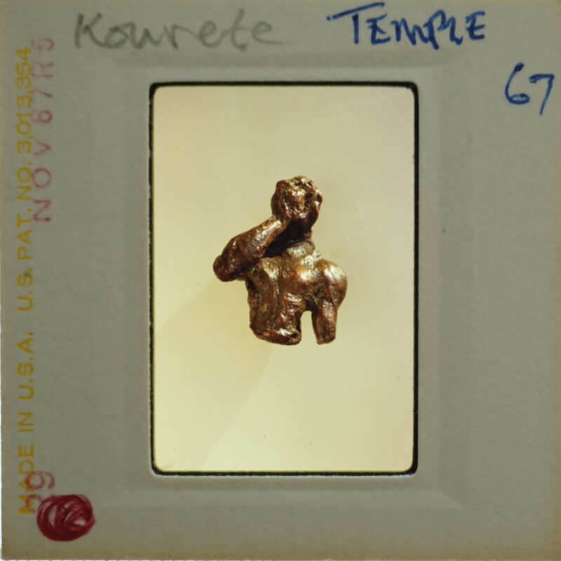 Small bronze sculpture of a figure with hands on face, displayed in a museum case.