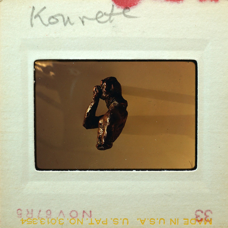 Small sculpture on display of person from the torso up from the side.