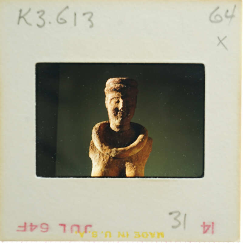 A photograph of an old, weathered clay sculpture with a humanoid form.