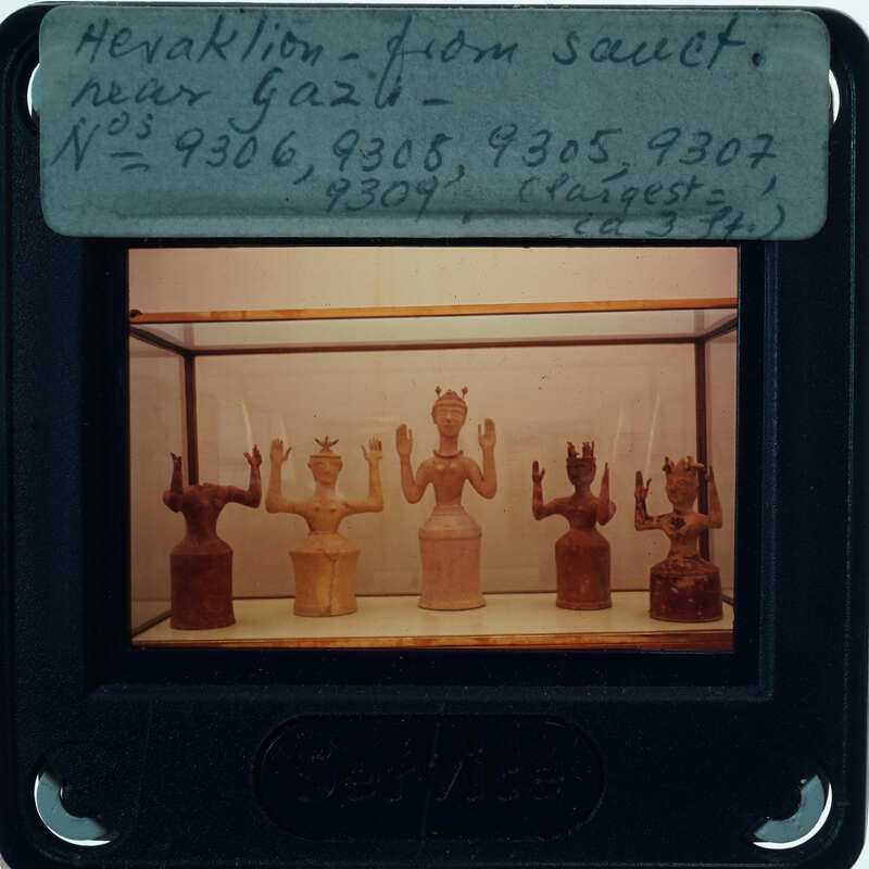 A collection of ancient Egyptian figurines displayed behind glass.