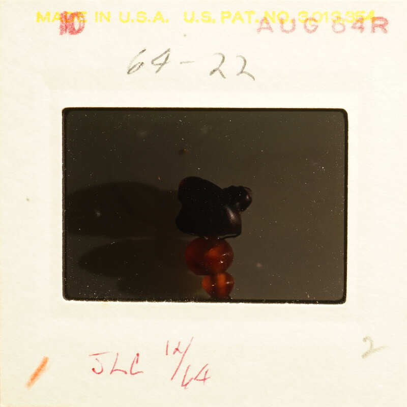 Small figurine with red and black colors on a white surface.