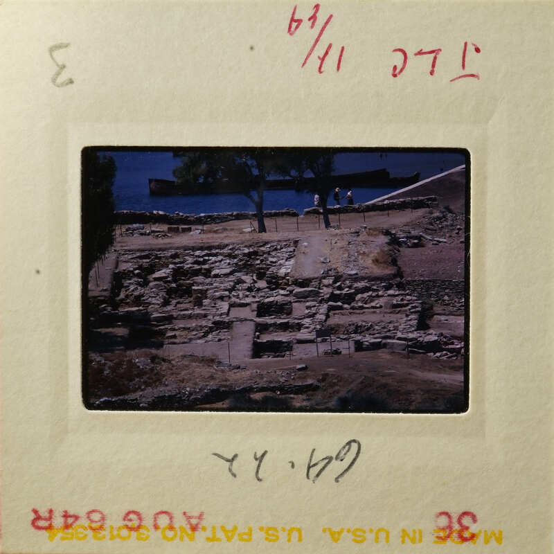 The photograph shows an ancient archaeological site with ruins and people exploring.