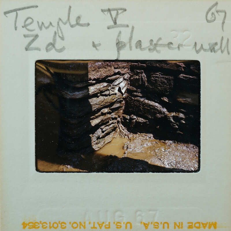 A photograph of a stone wall with a handwritten label on an old film strip.
