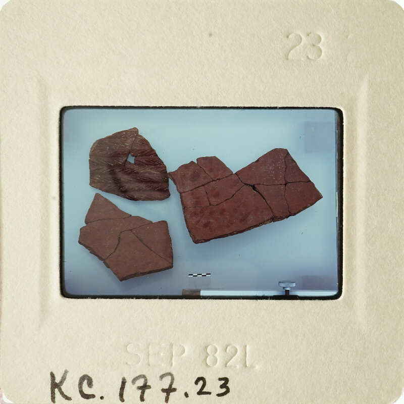 Broken brown pottery on a white surface.