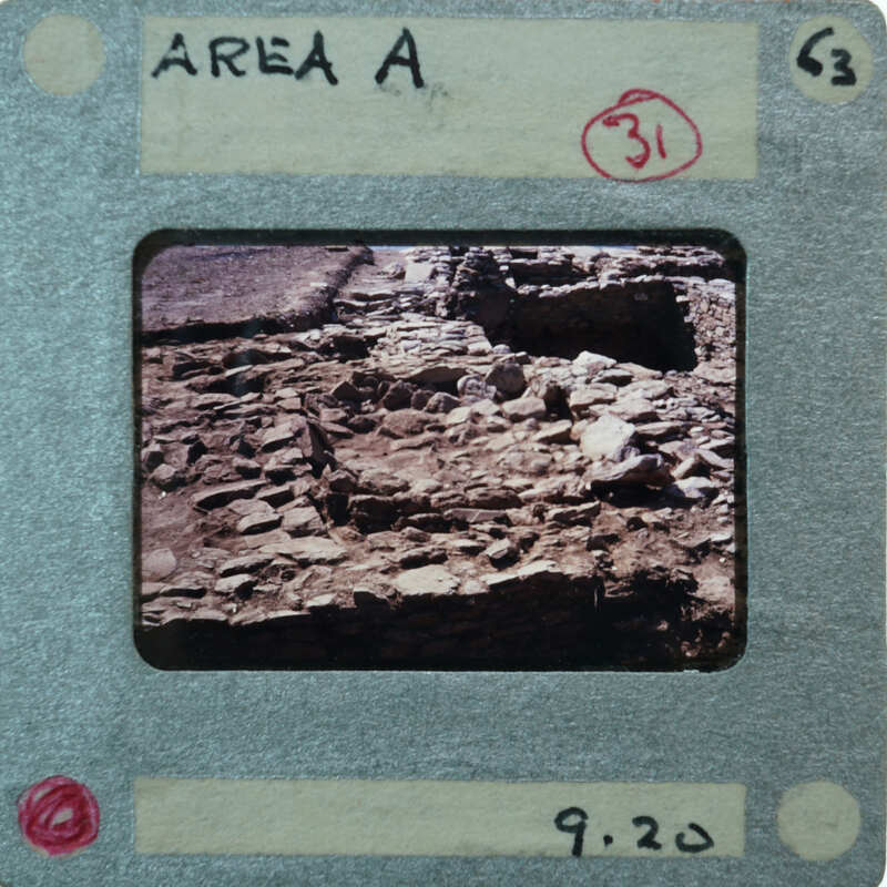 A photograph of an archaeological site with ruins and rubble, enclosed within a film strip frame.
